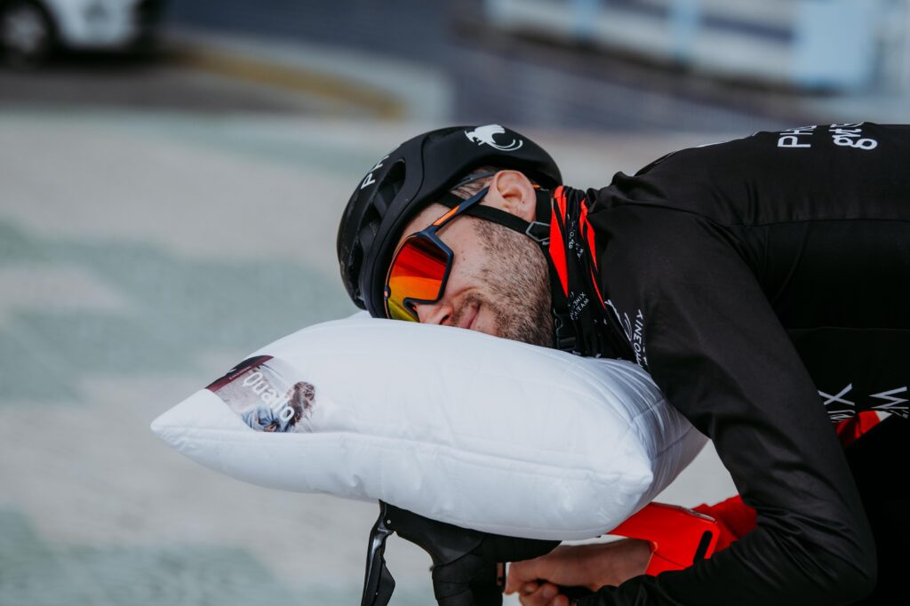 Triathlonista na rowerze, który leży na poduszce znajdującej się na kierownicy jego roweru