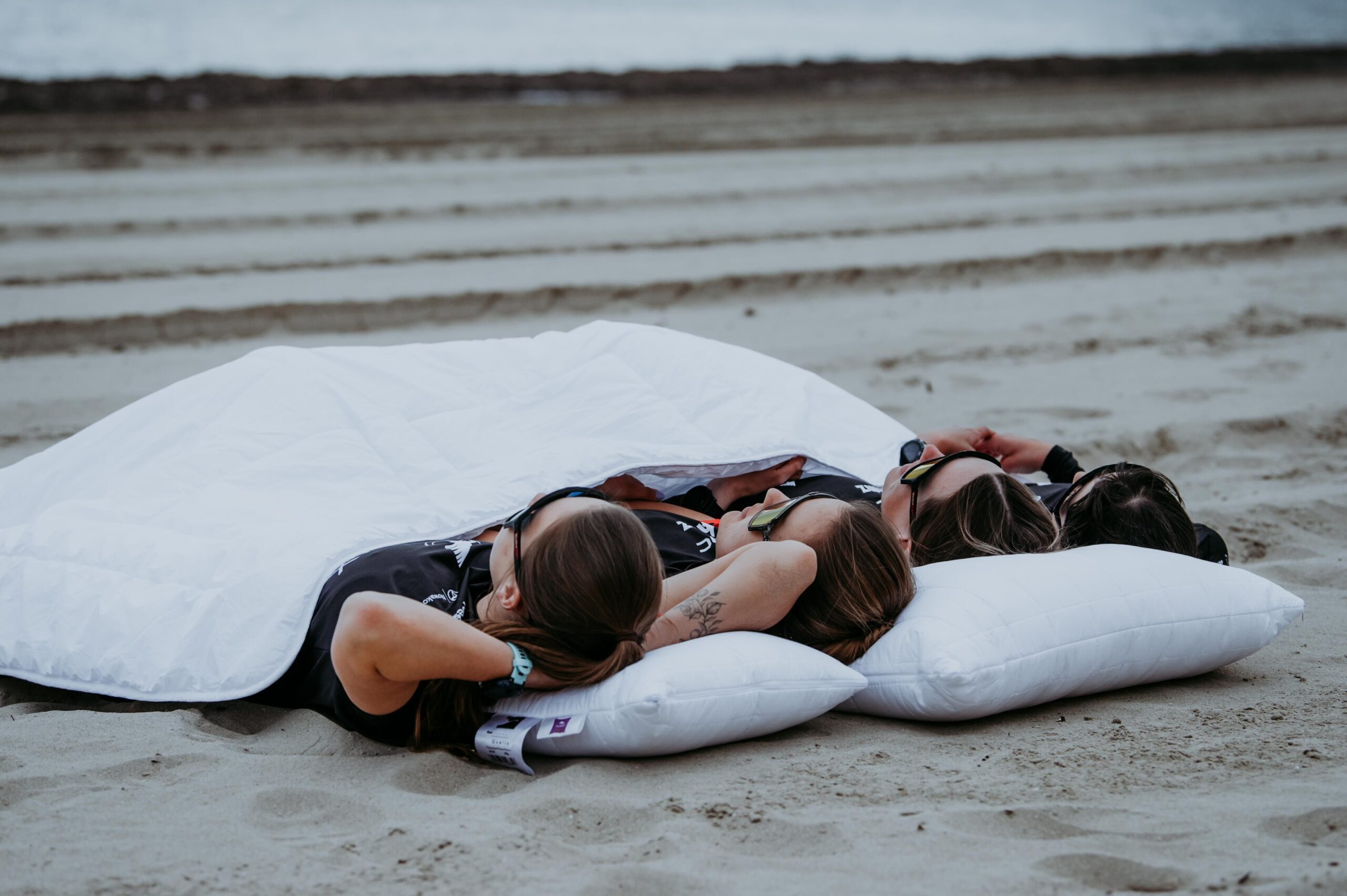 Zawodniczki Pho3nix GVT Team na plaży w Calpe leżące pod kołdrą AMZ